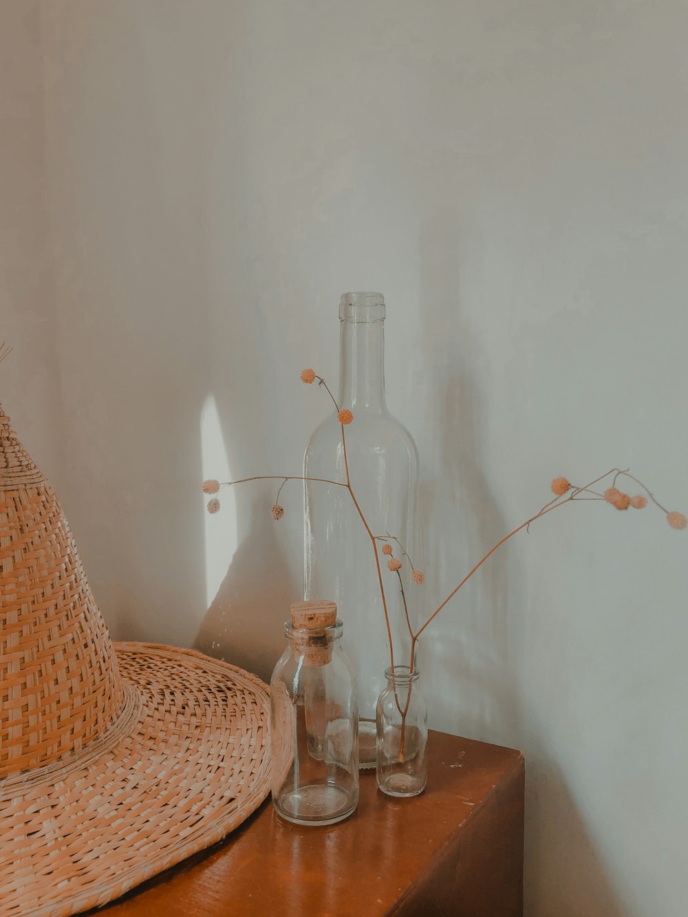 chapeau tissé marron à côté de bouteilles en verre transparent sur une table en bois marron