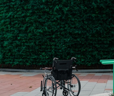 black bicycle parked beside green wall