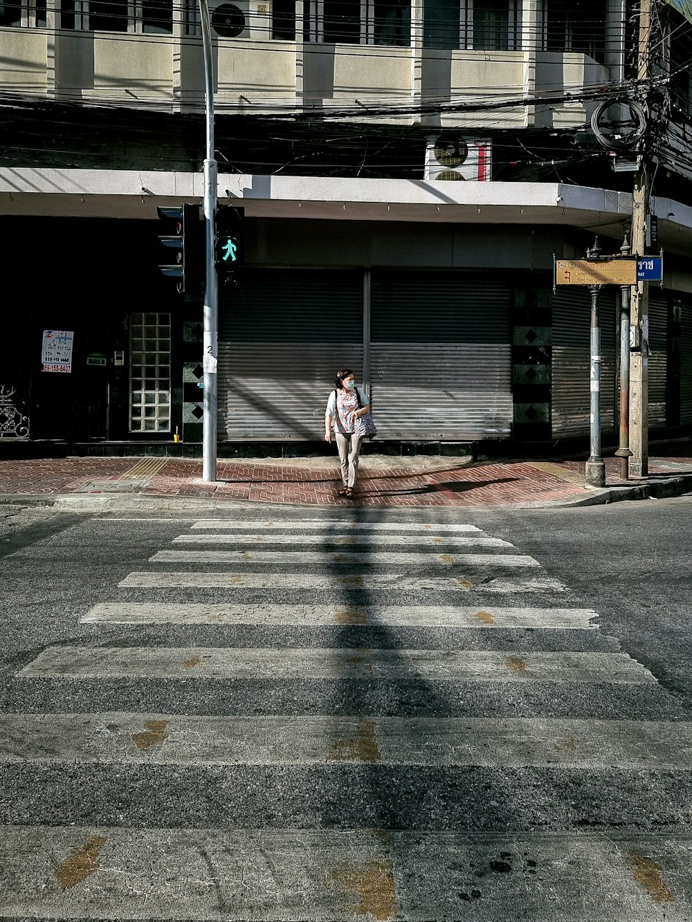 man in white shirt walking on sidewalk during daytime