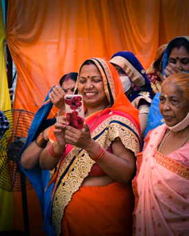 A woman happily browsing sarees on her smartphone in a cozy setting.