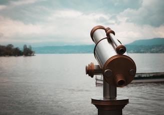 brown and silver telescope near body of water during daytime