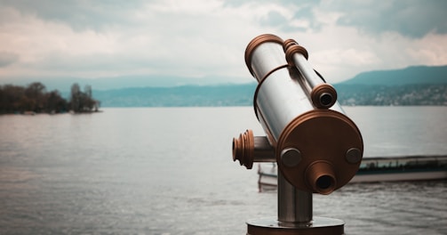 brown and silver telescope near body of water during daytime