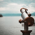 brown and silver telescope near body of water during daytime