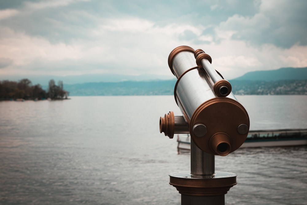 brown and silver telescope near body of water during daytime