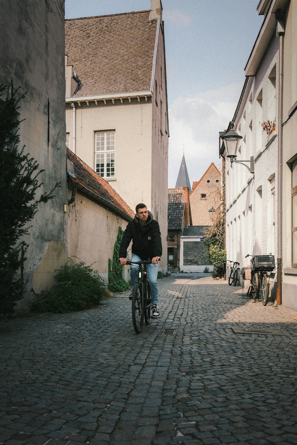 man in black jacket riding bicycle on street during daytime