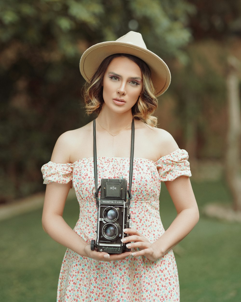 woman in white and pink floral dress holding camera