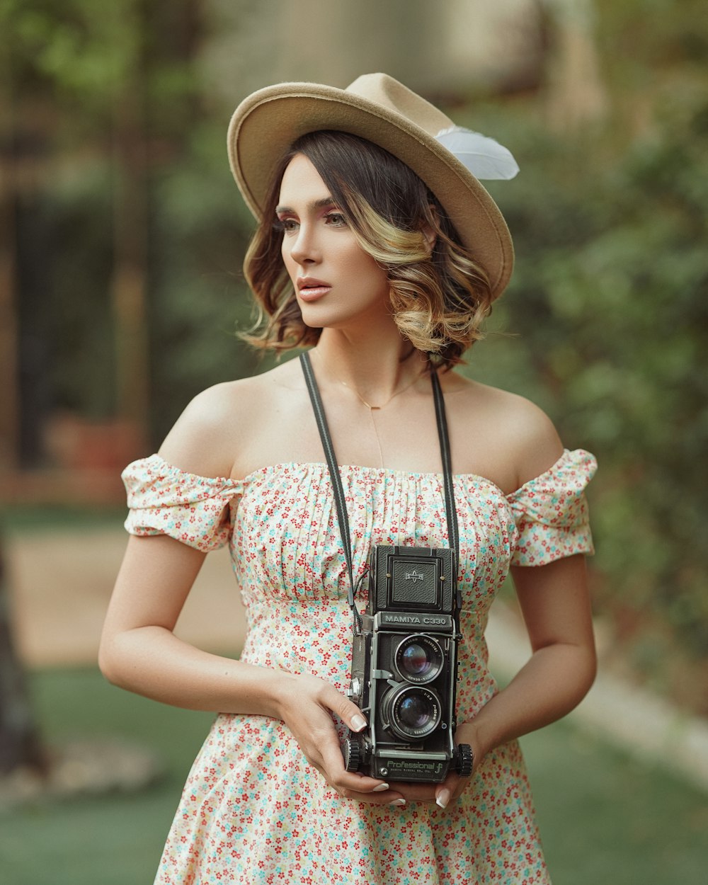 woman in white and red floral dress holding black camera