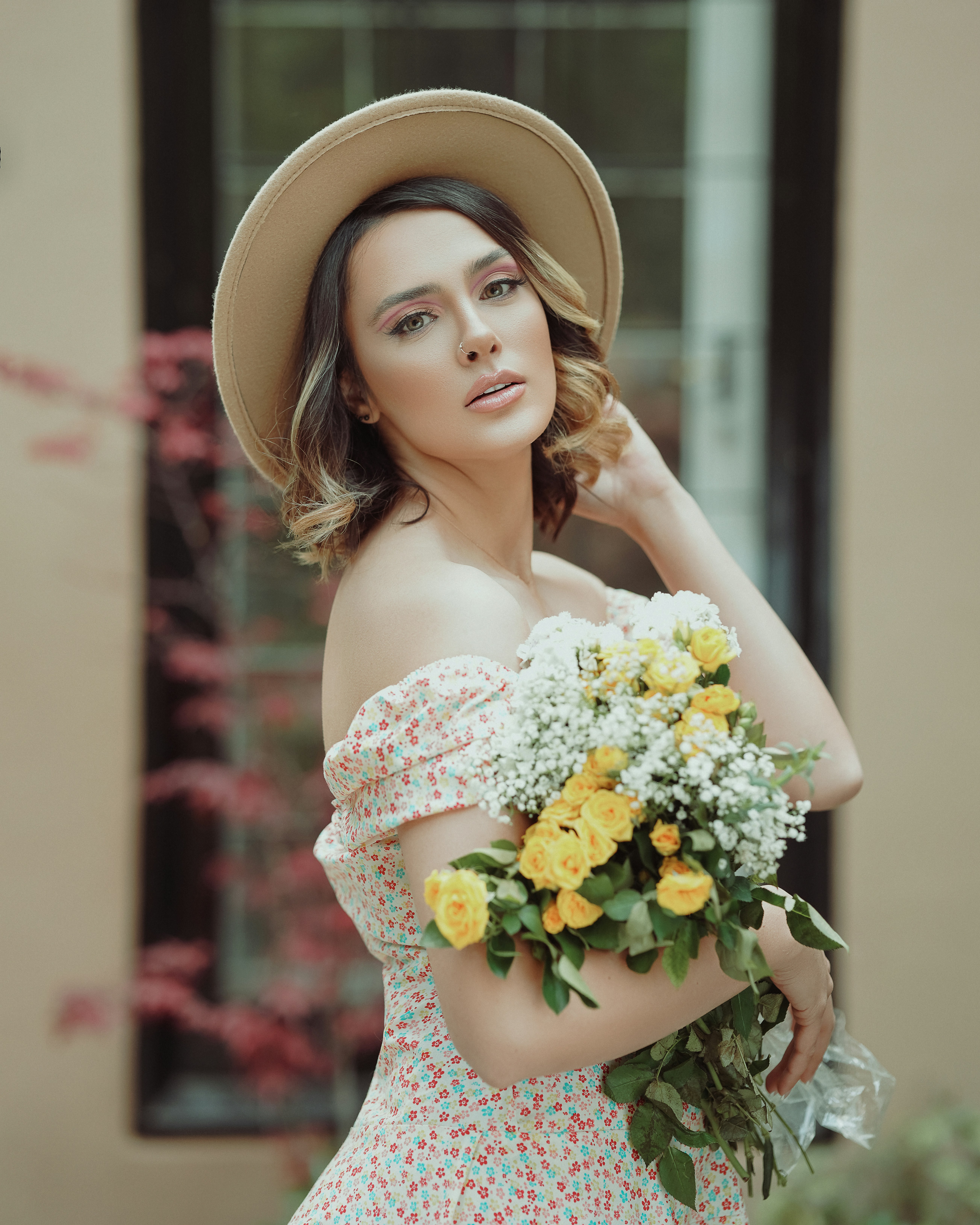 白い花束を持っている白とピンクの花柄のオフショルダードレスの女性
