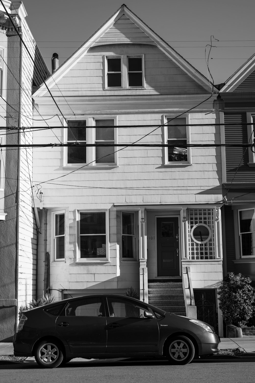 grayscale photo of car parked in front of house