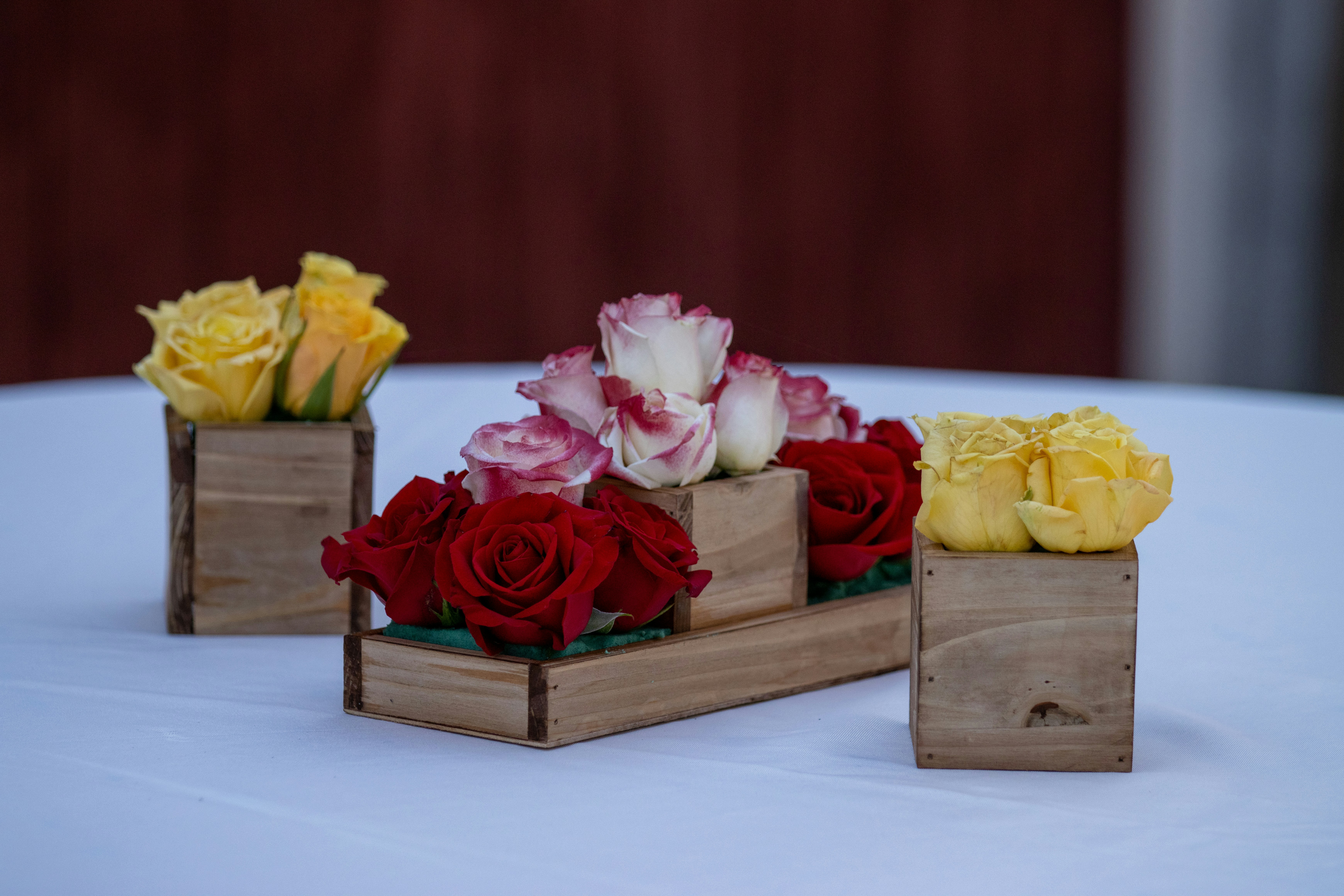 A flat lay of various colorful flowers like roses, daisies, and sunflowers arranged on a rustic wooden table.