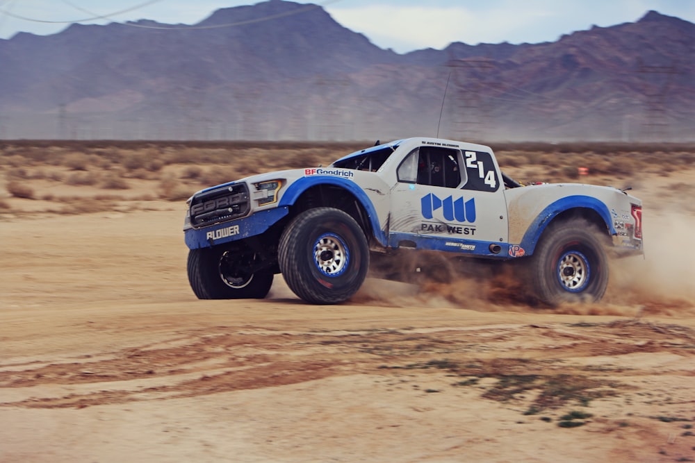 white and blue monster truck on desert during daytime