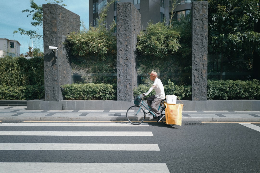 man in white shirt riding bicycle on road during daytime