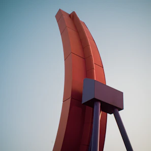 Custom fabricated metal sculpture with orange accents, displayed outdoors against a grey wall