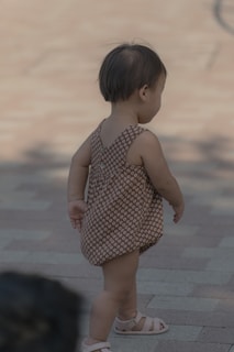 girl in white and black polka dot dress standing on gray concrete floor during daytime