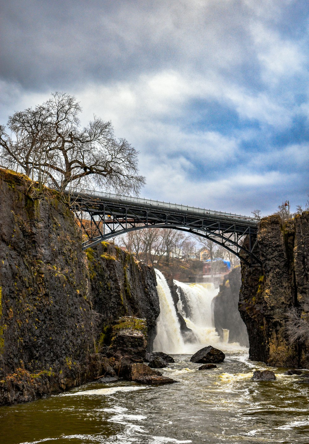 bridge over water falls under white clouds during daytime