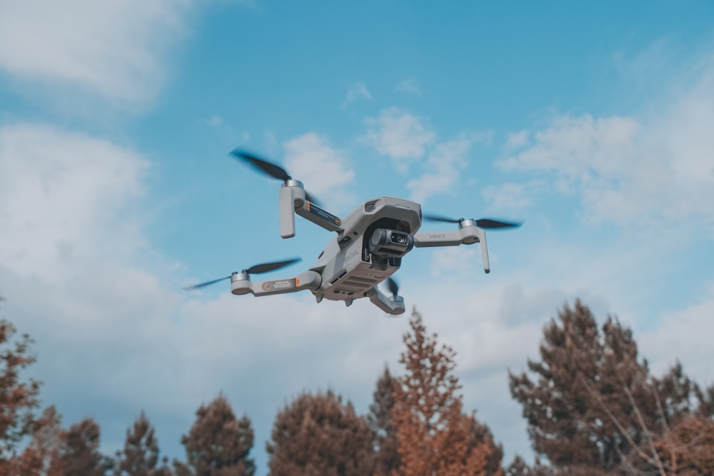 white and black drone flying in mid air during daytime