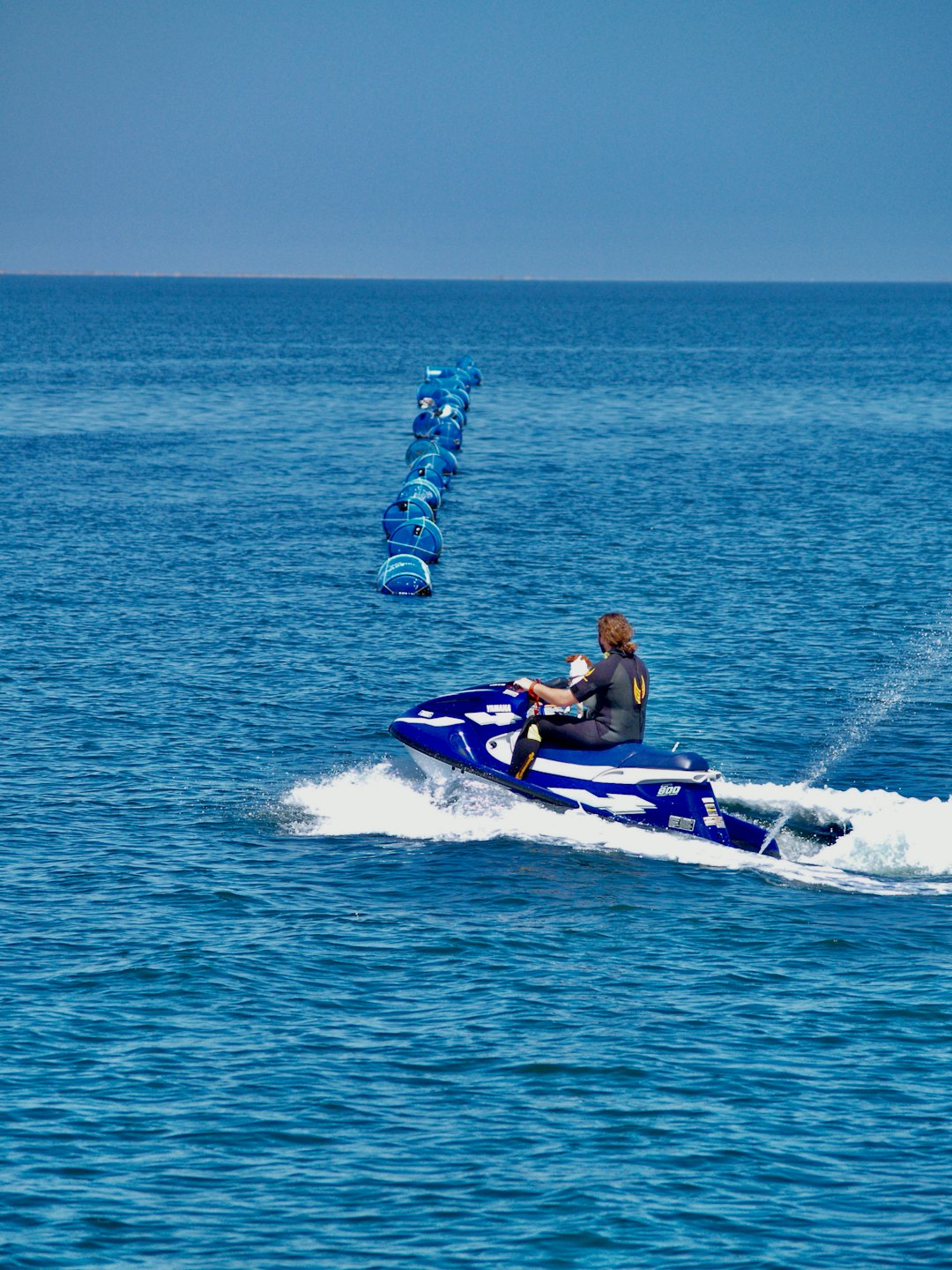 woman in blue and white wetsuit riding white and purple inflatable raft on blue sea during