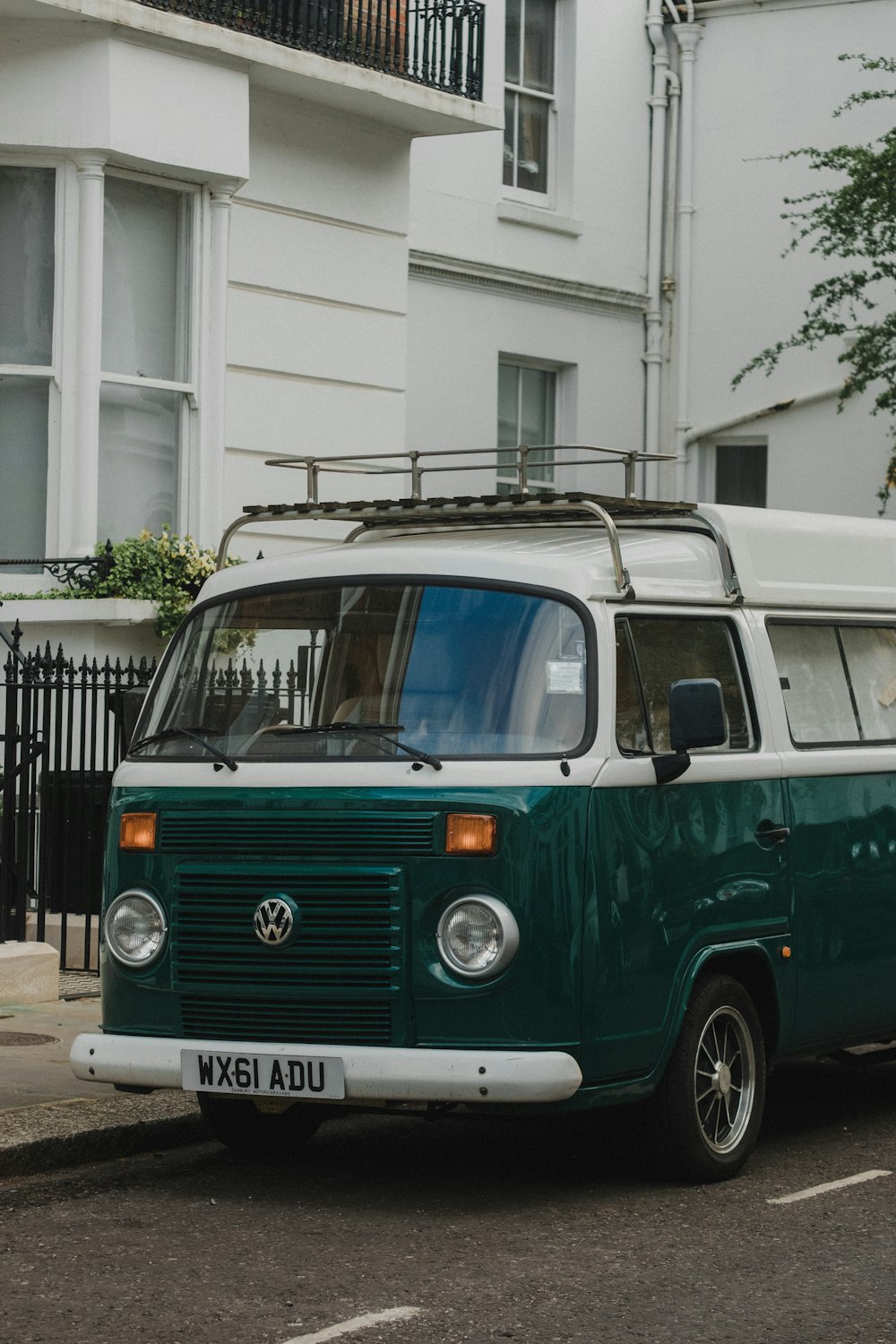 green and white volkswagen t-2 parked on sidewalk during daytime