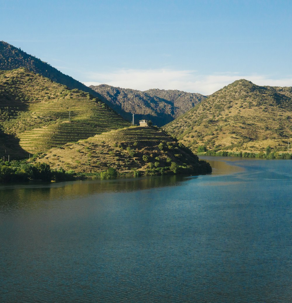 Grüne Berge am Fluss unter blauem Himmel tagsüber