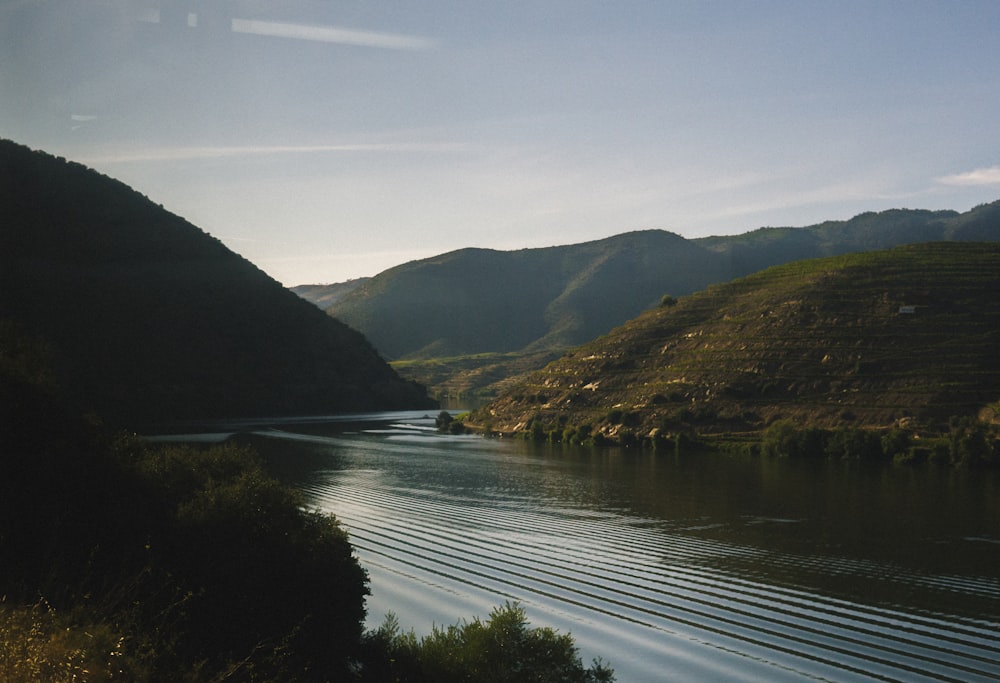 lake in the middle of green mountains during daytime