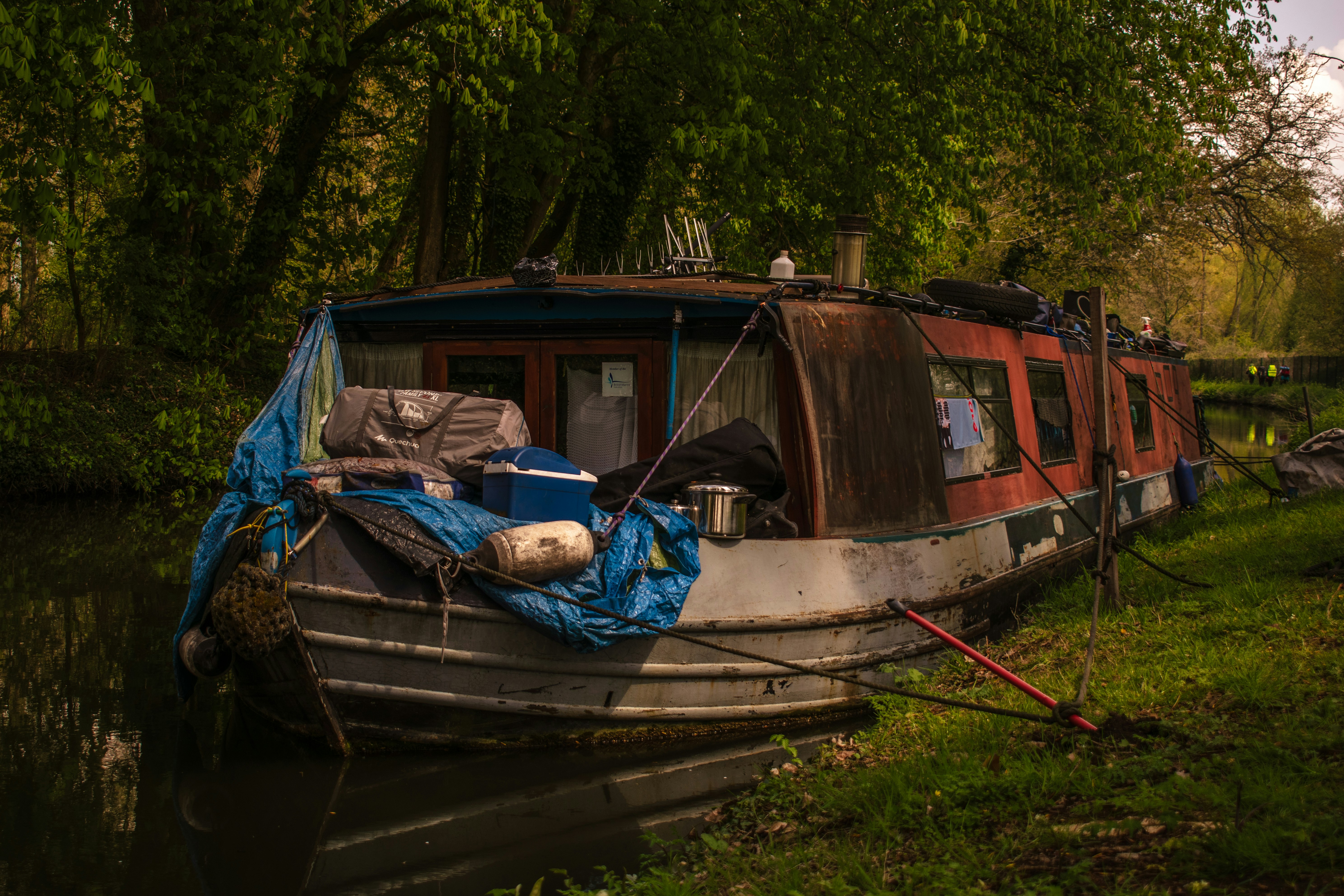 brown and white wooden boat on green grass during daytime, making a home on the canal