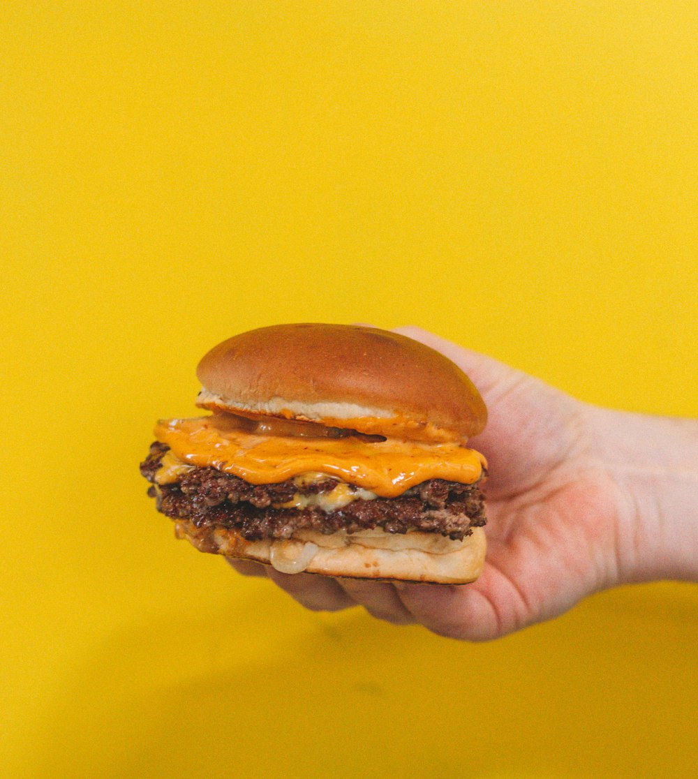 person holding burger with patty