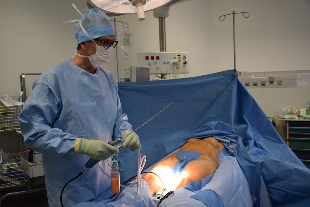 man in blue scrub suit holding white hose