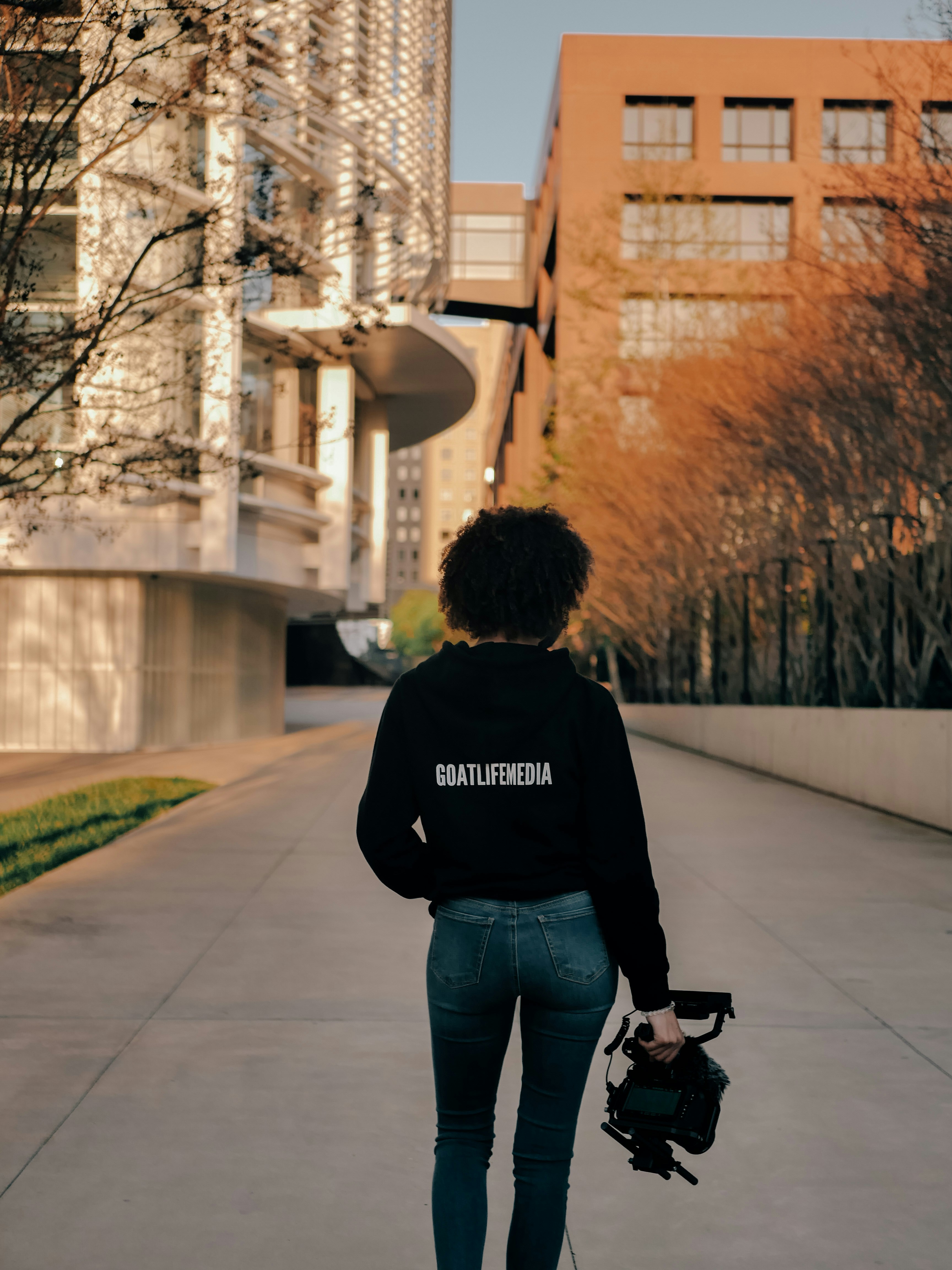 man in black hoodie and blue denim jeans walking on sidewalk during daytime