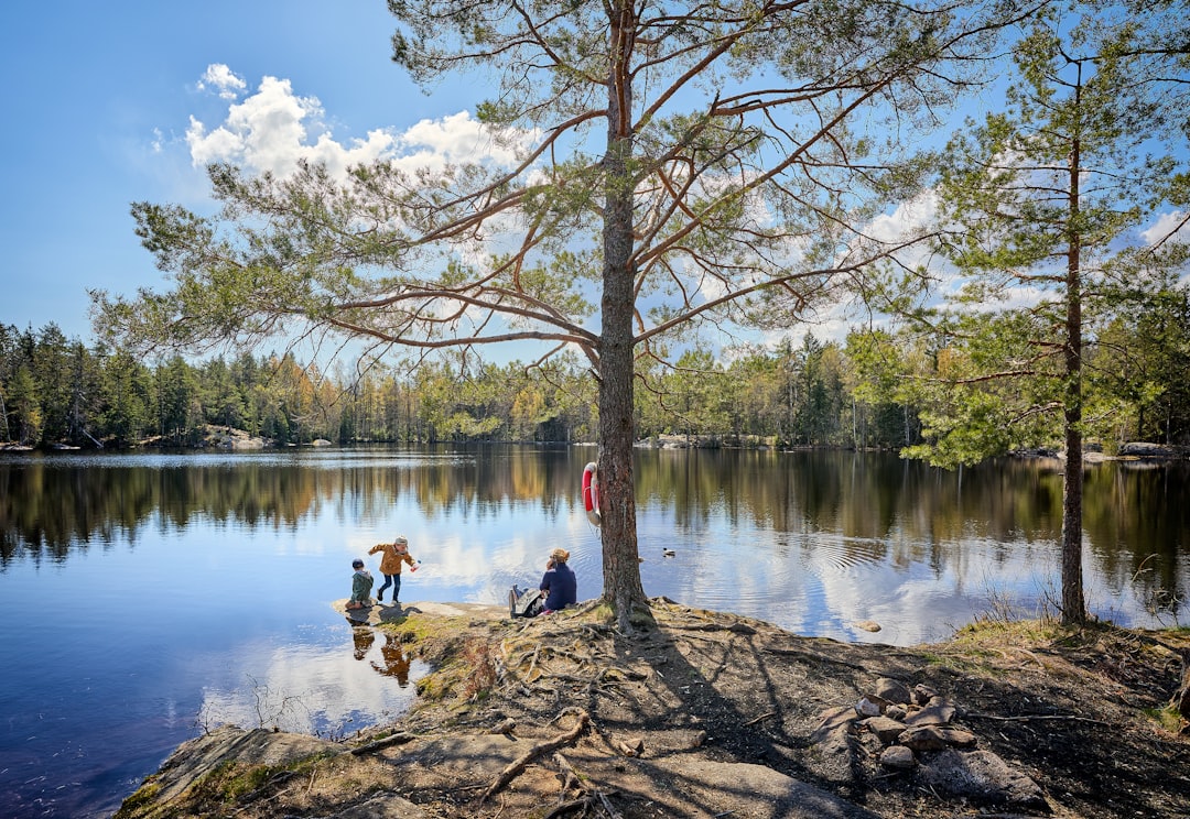 man in white shirt sitting on brown rock near body of water during daytime