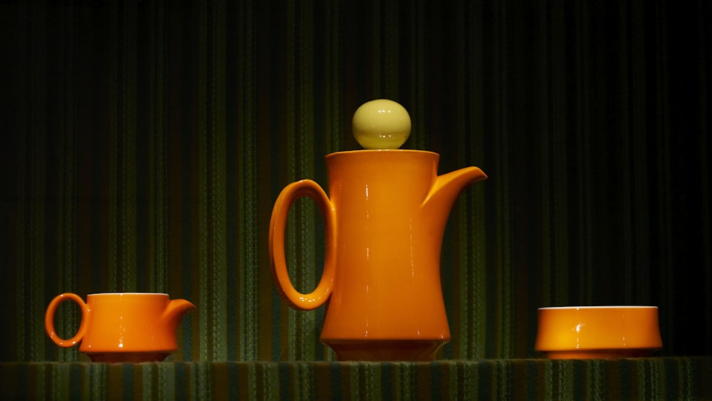 orange ceramic teapot on red textile
