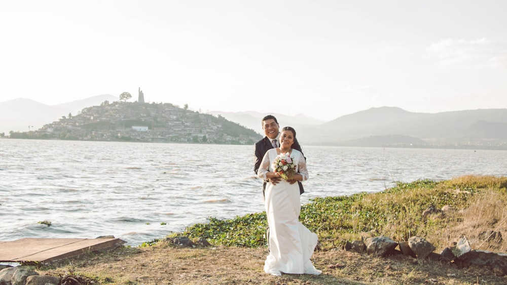 man and woman standing on brown field near body of water during daytime