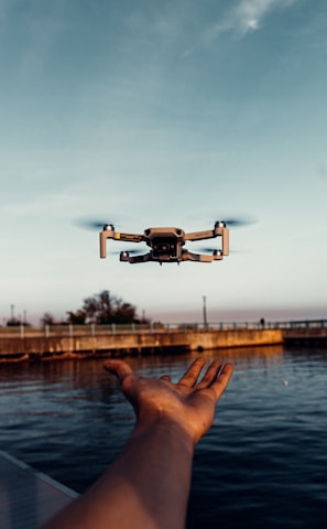 white drone flying over the sea during daytime