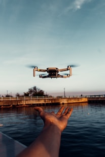 white drone flying over the sea during daytime