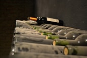 A rustic wine cellar with bottles neatly arranged, bathed in soft greenish light.
