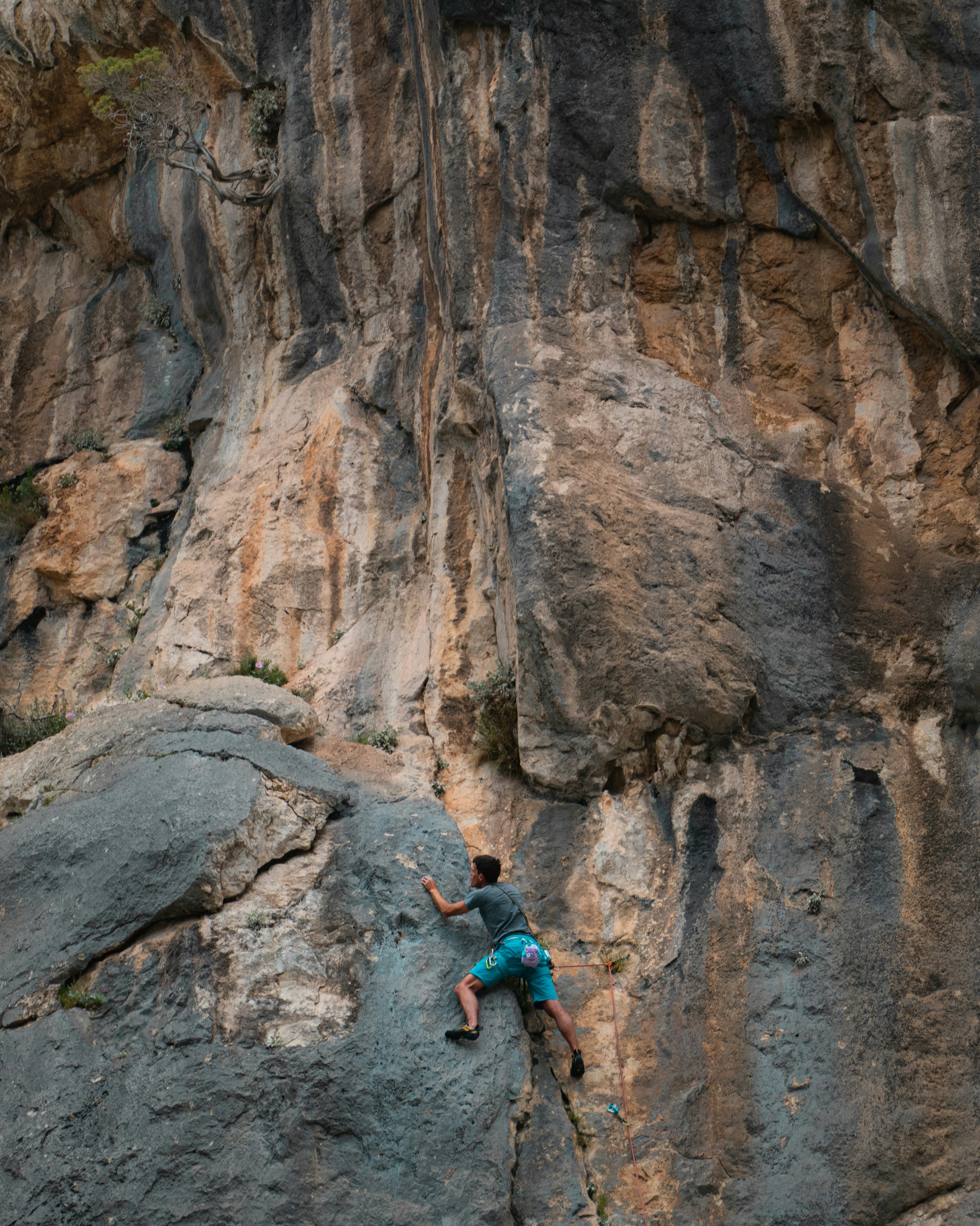 woman in blue tank top climbing on brown rock formation during daytime