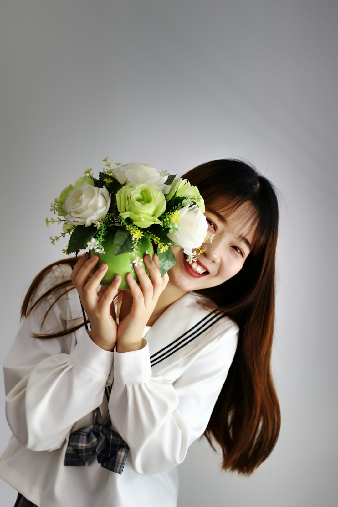 woman in white long sleeve shirt holding bouquet of white roses