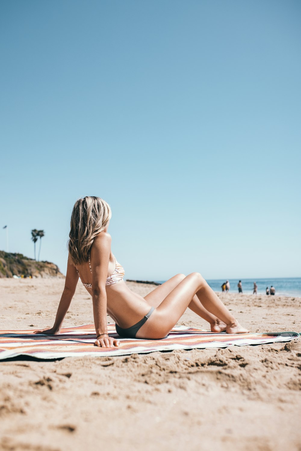 woman in black bikini lying on beach sand during daytime