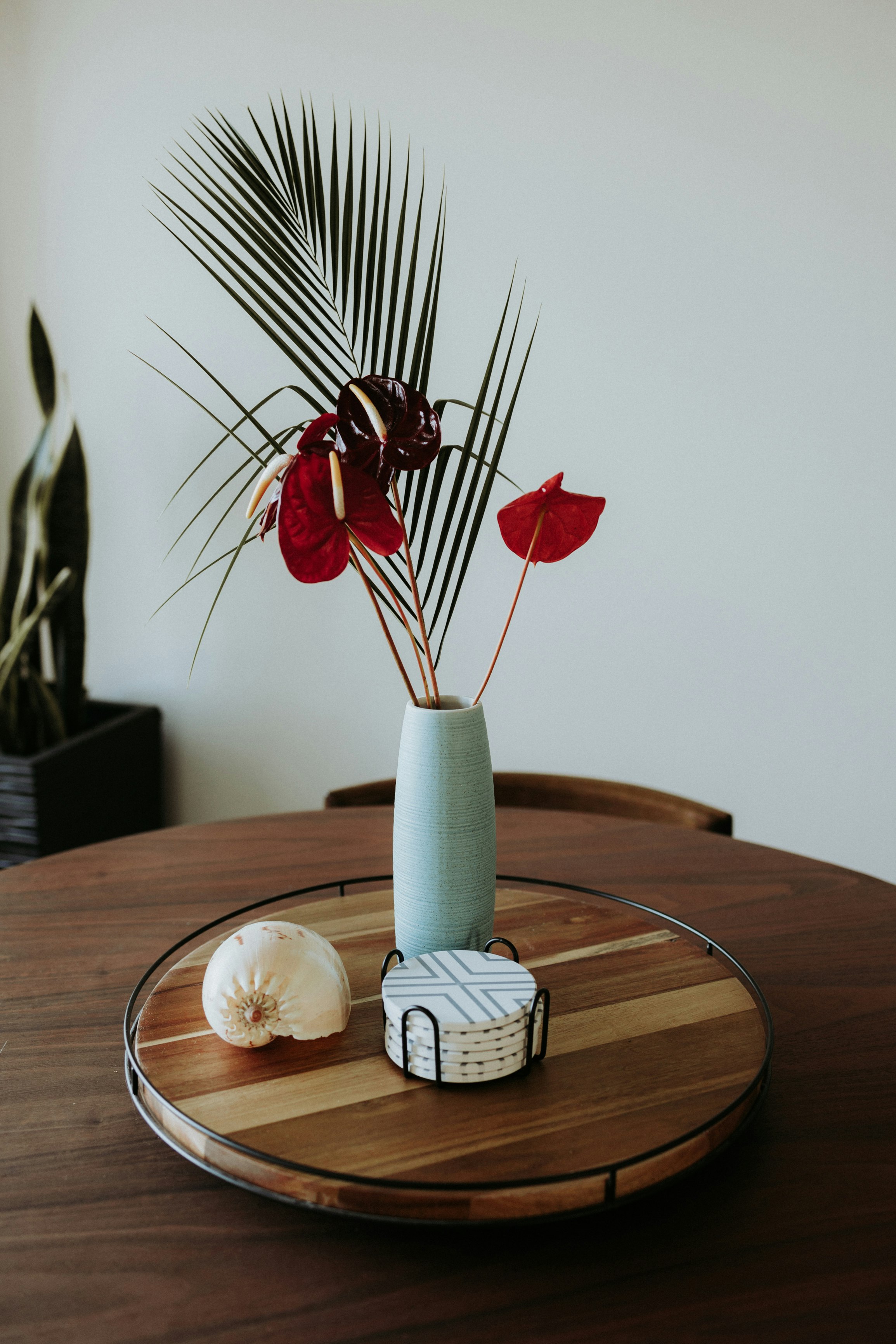 red flowers in green ceramic vase on brown wooden table