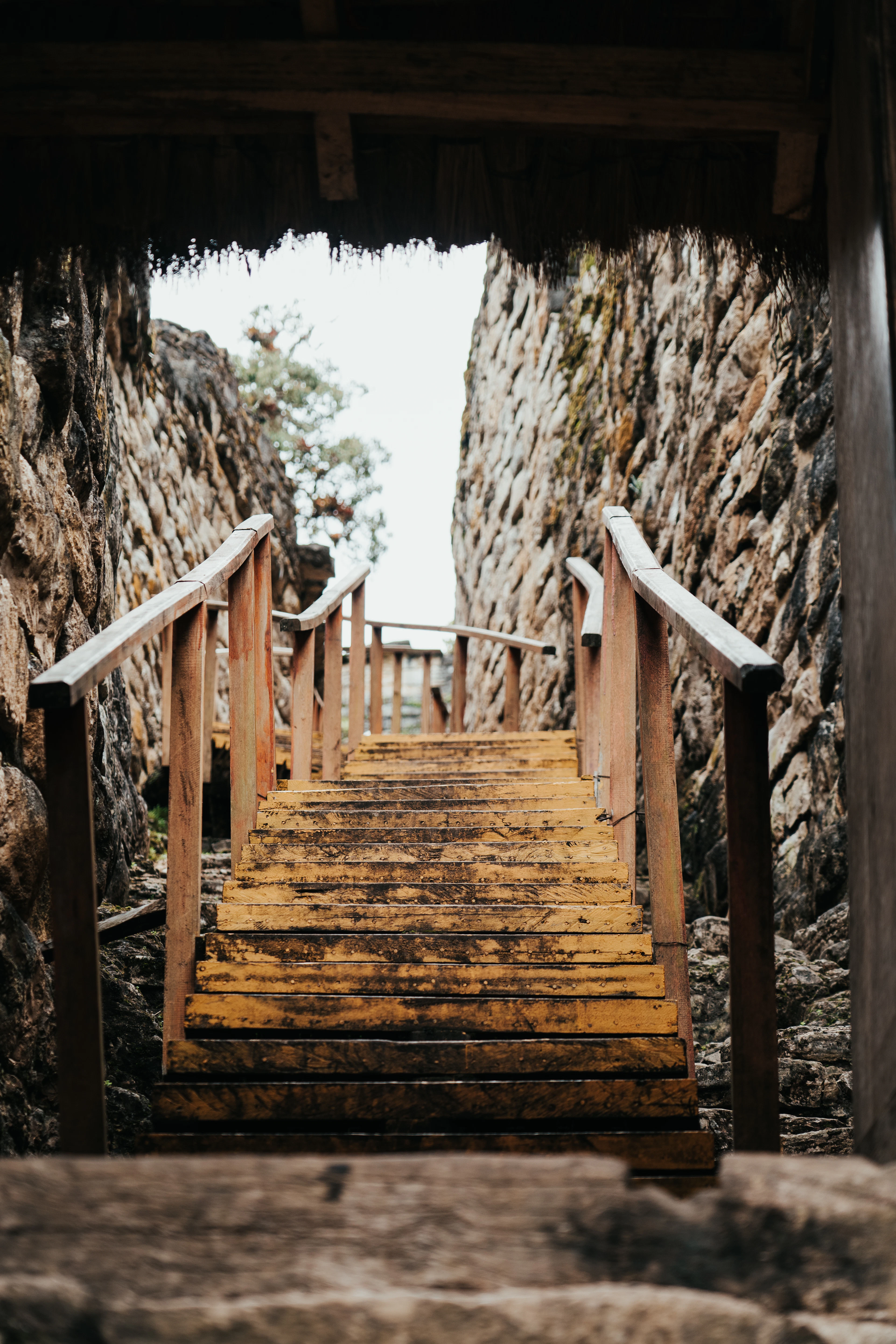 Wooden steps through a narrow entrance between the high stone walls of Kuélap