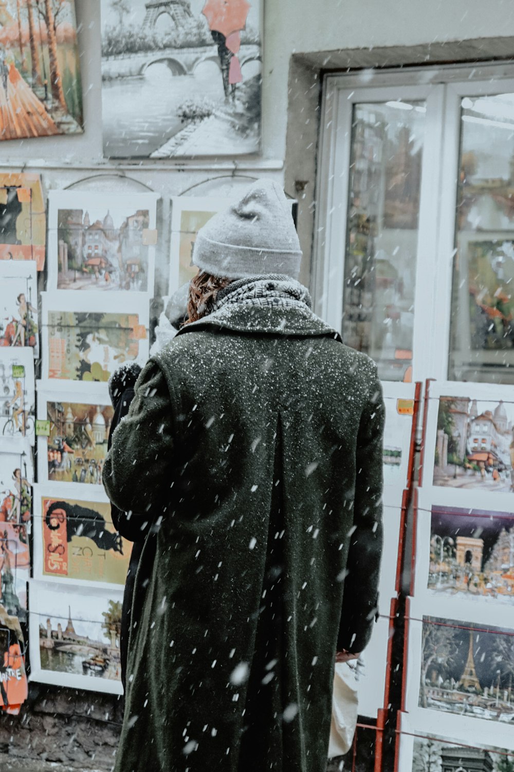 person in gray hoodie standing near white wooden shelf