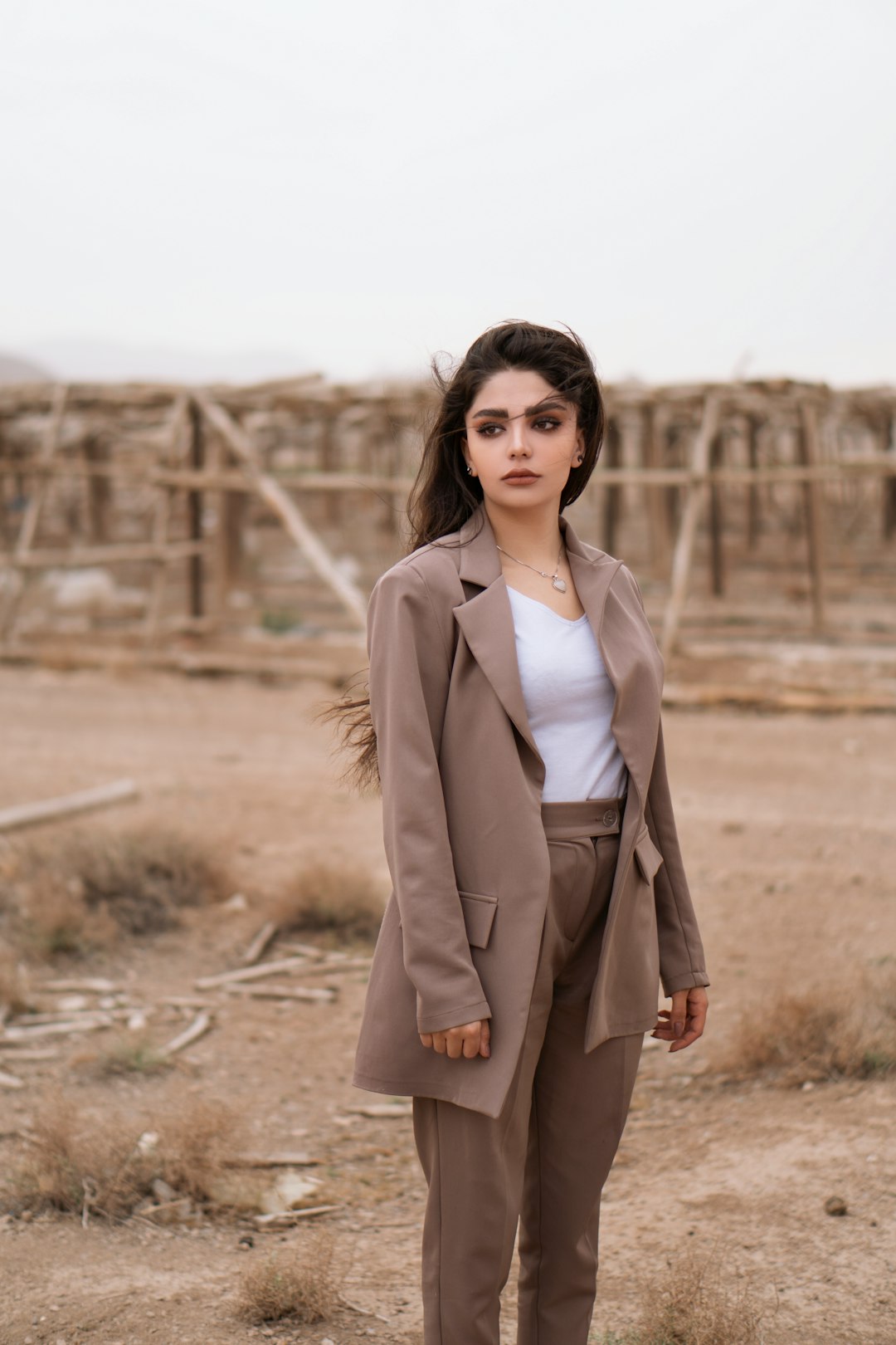 woman in brown coat standing on brown field during daytime