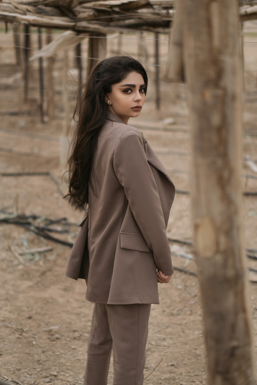 woman in brown coat standing on brown dirt ground during daytime