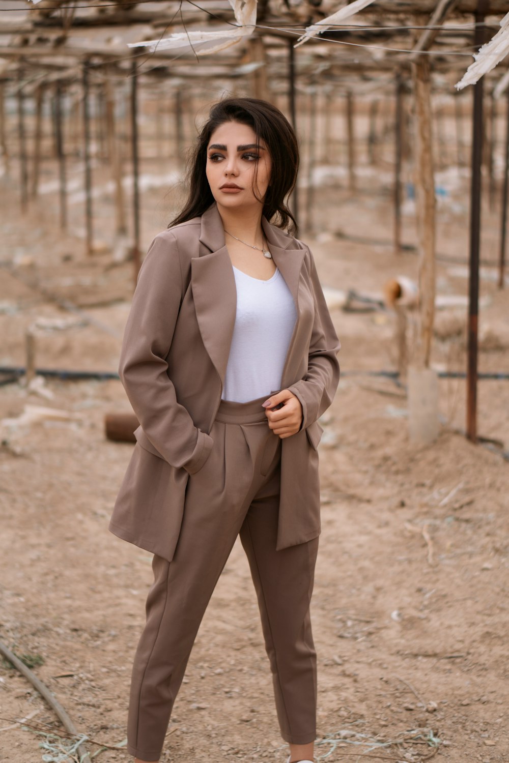 woman in brown blazer standing on brown sand during daytime