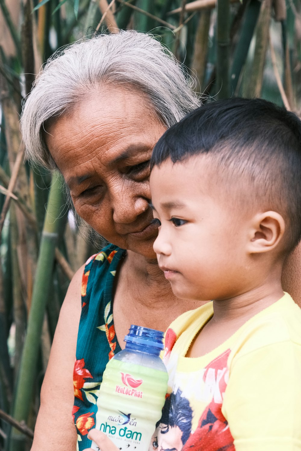 woman in yellow shirt carrying child in blue and yellow shirt