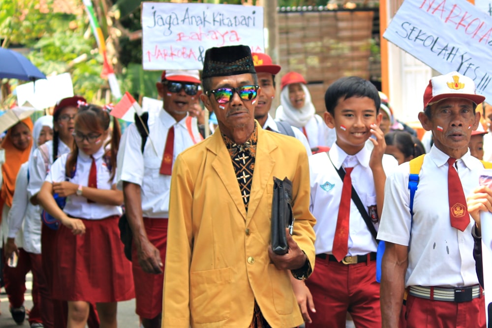 man in yellow suit standing near people during daytime