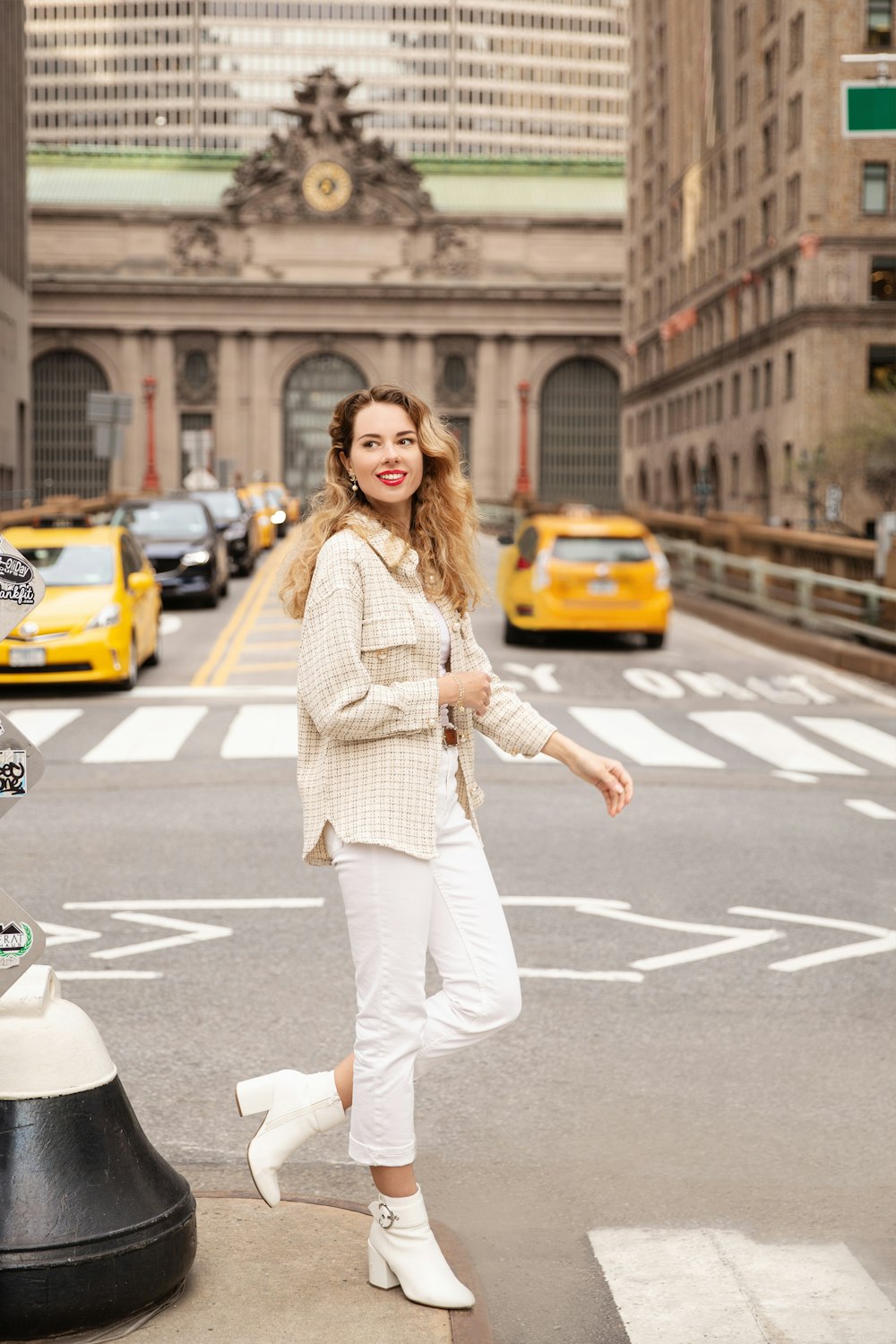 woman in white and black checkered dress shirt and white pants standing on road during daytime