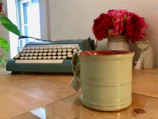 Elegant workspace with a vintage typewriter, fresh flowers, and manuscript drafts.