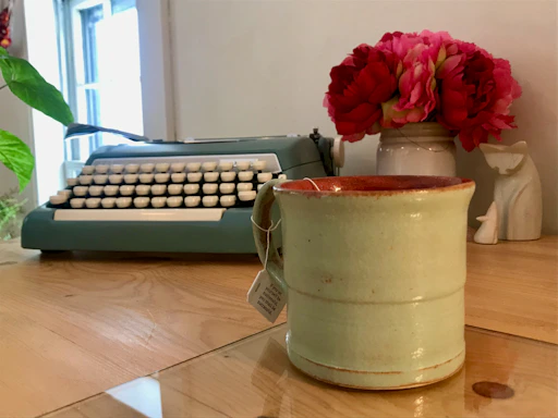 A cozy workspace with a vintage typewriter and soft pink roses around it, reflecting passion for romantic writing.