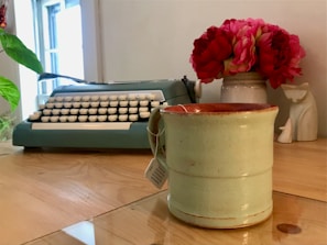 A creative workspace featuring a vintage typewriter, scattered pages, and a bold purple coffee mug glowing under soft light.