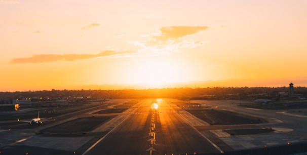 Sunset view of a runway with a jet preparing for takeoff.